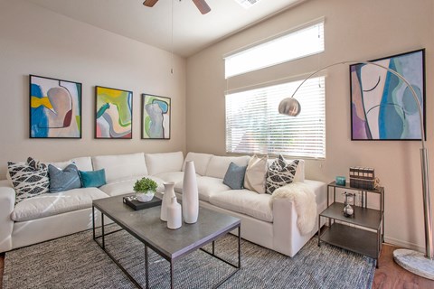 a living room with couches and tables and a window
